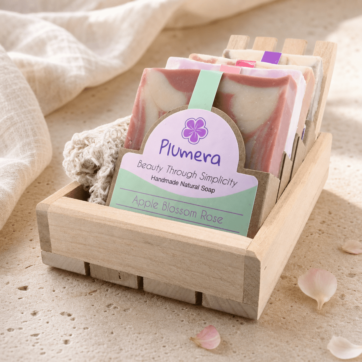 Floral Soap Box — Editorial Main Image Plumera Floral Soap Box with four pink and pastel handmade bars, wooden soap dish, agave fiber soap saver, and wood box