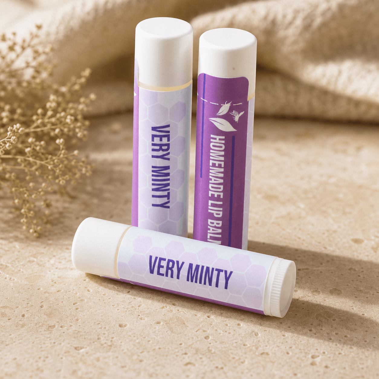 Three Plumera Very Minty handmade lip balm tubes with purple and white labels on a black background